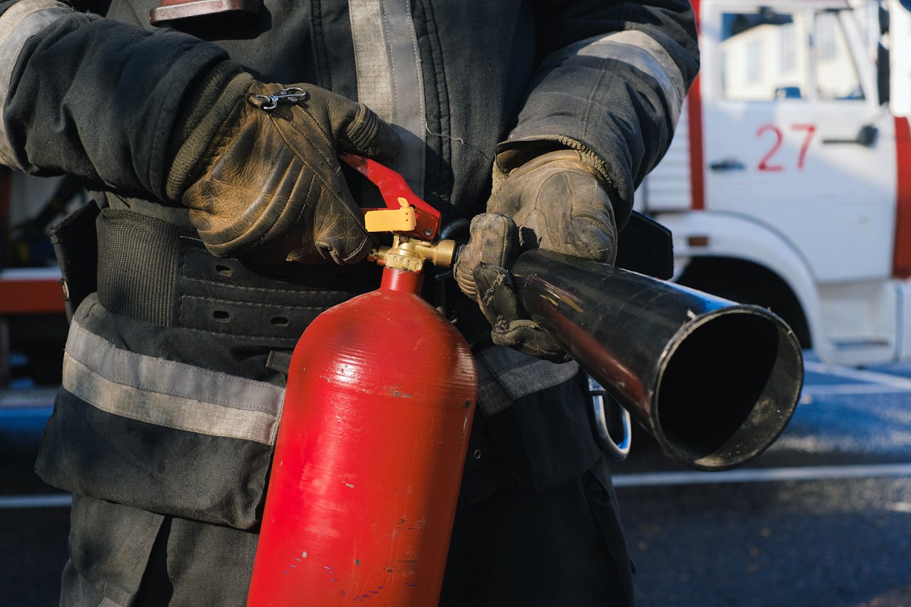 Firefighter in uniform holding a fire extinguisher, emphasizing safety and emergency readiness.